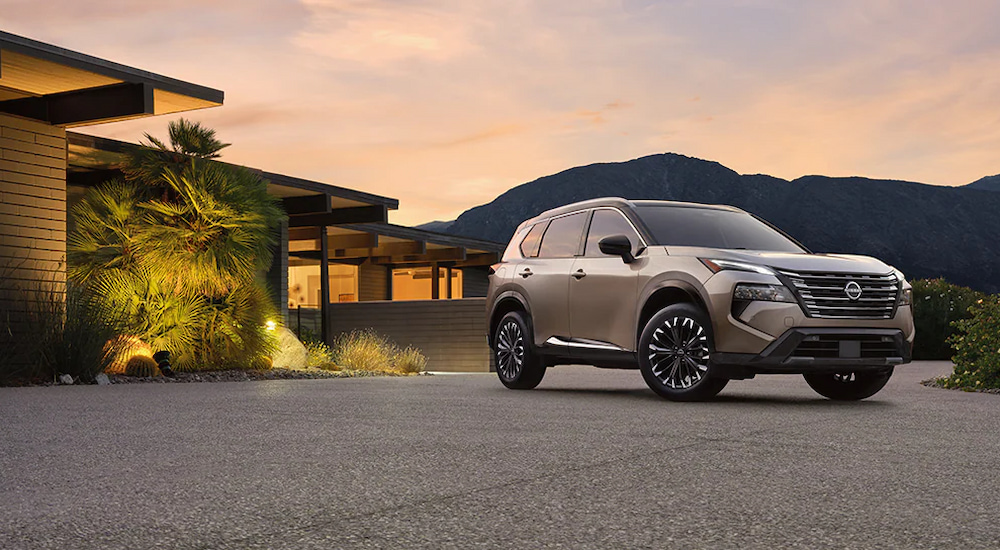 A silver 2025 Nissan Rogue Platinum parked outside a house at dusk.