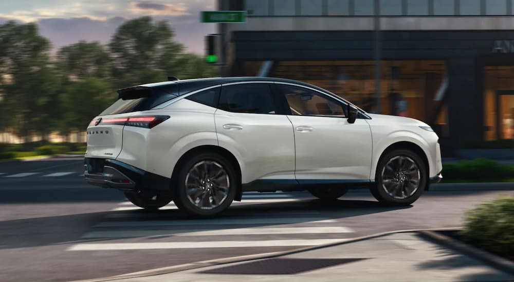 Side of a white 2025 Nissan Murano driving in a city.