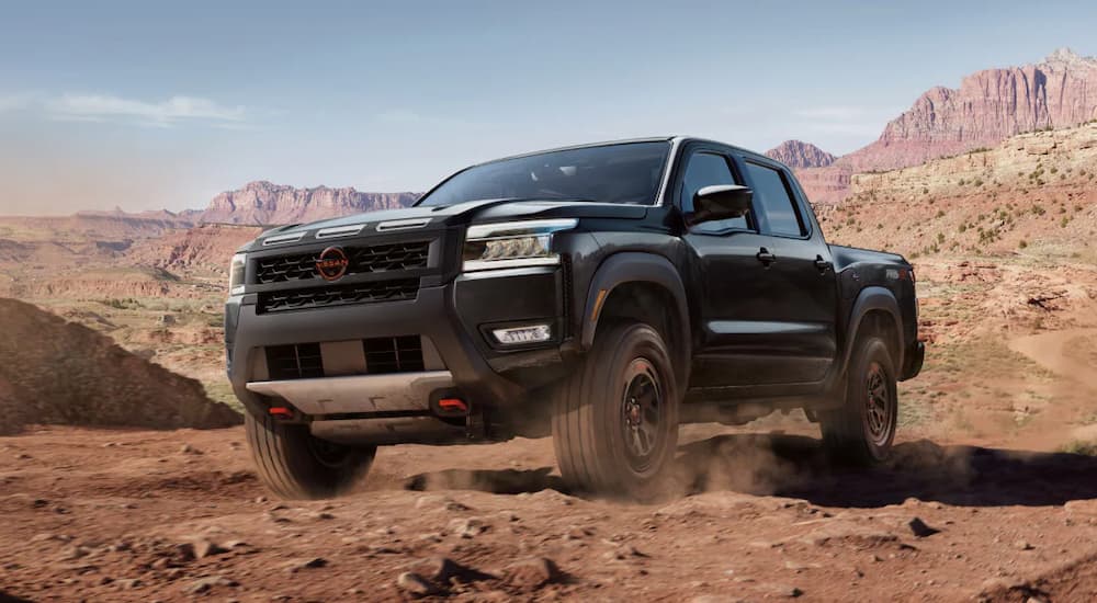 Black 2025 Nissan Frontier driving across a desert.