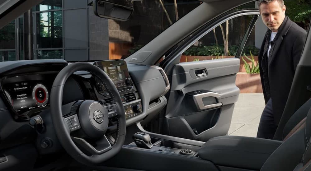 A person entering the black interior of a 2025 Nissan Pathfinder available at a Nissan dealer near Fridley.