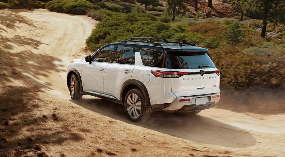 Rear of a white 2025 Nissan Pathfinder Rock Creek driving off-road.