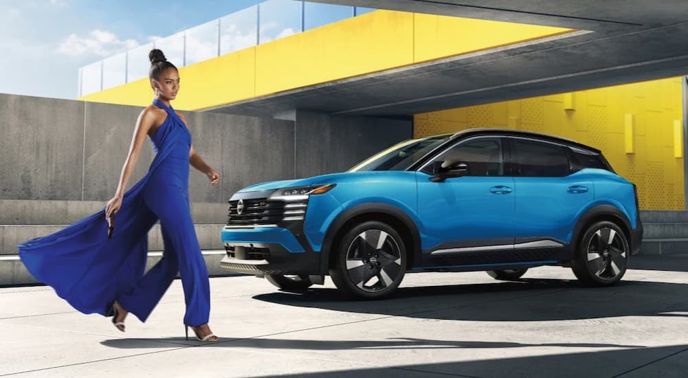 A person walking near a blue 2026 Nissan Kicks.