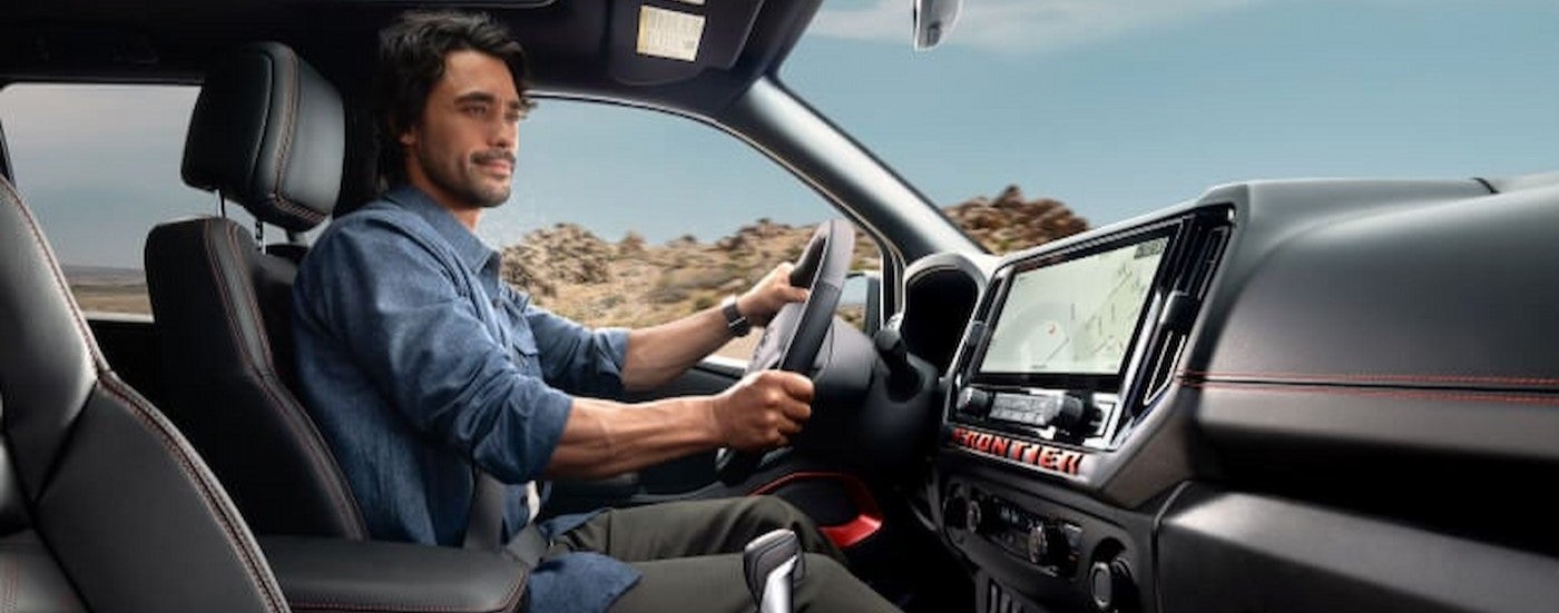 A person driving in a 2025 Nissan Frontier.