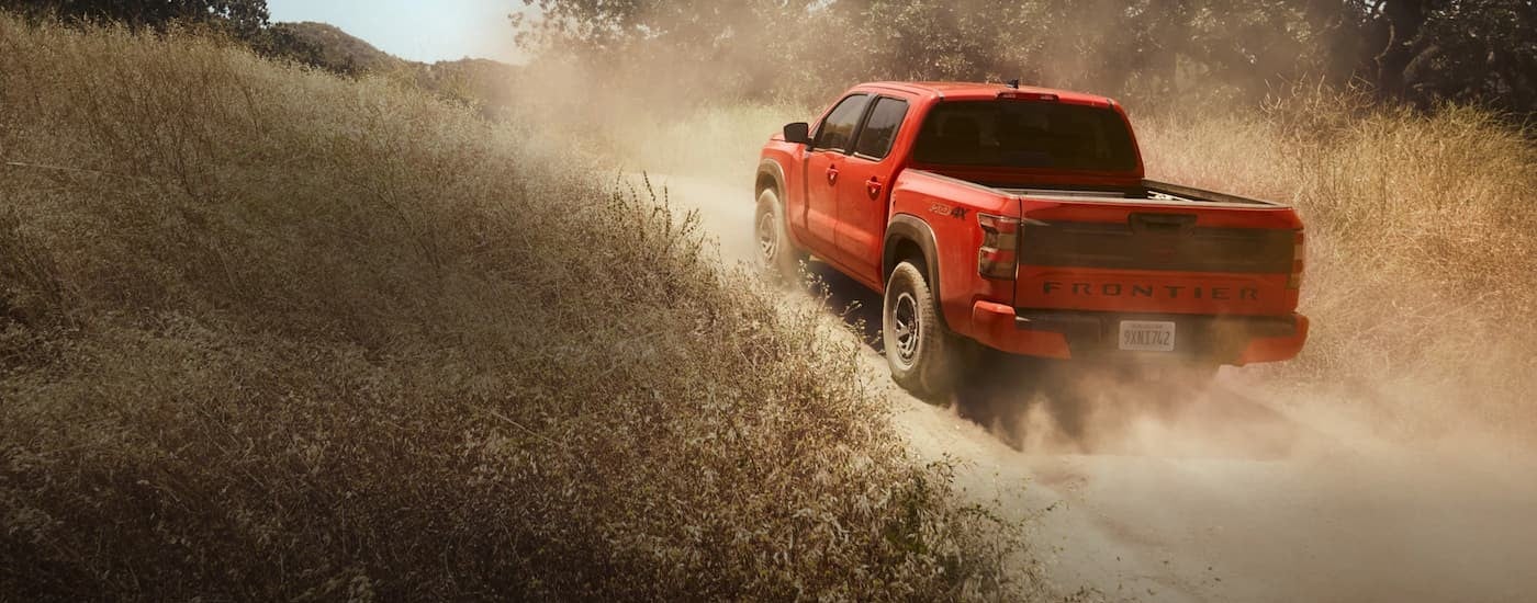 An orange 2025 Nissan Frontier driving off-road.
