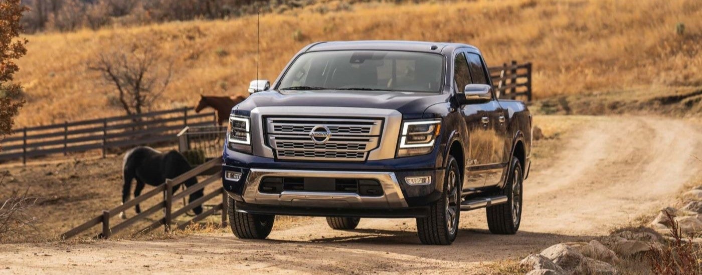A black 2021 Nissan Titan parked near horses on a farm.