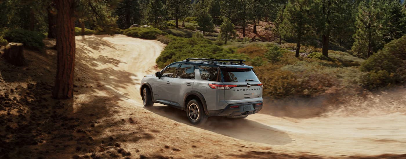 Grey 2025 Nissan Pathfinder driving on a dirt road.