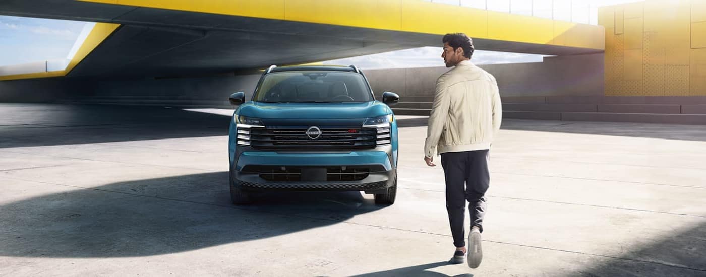 A blue 2025 Nissan Kicks SR parked near a person.