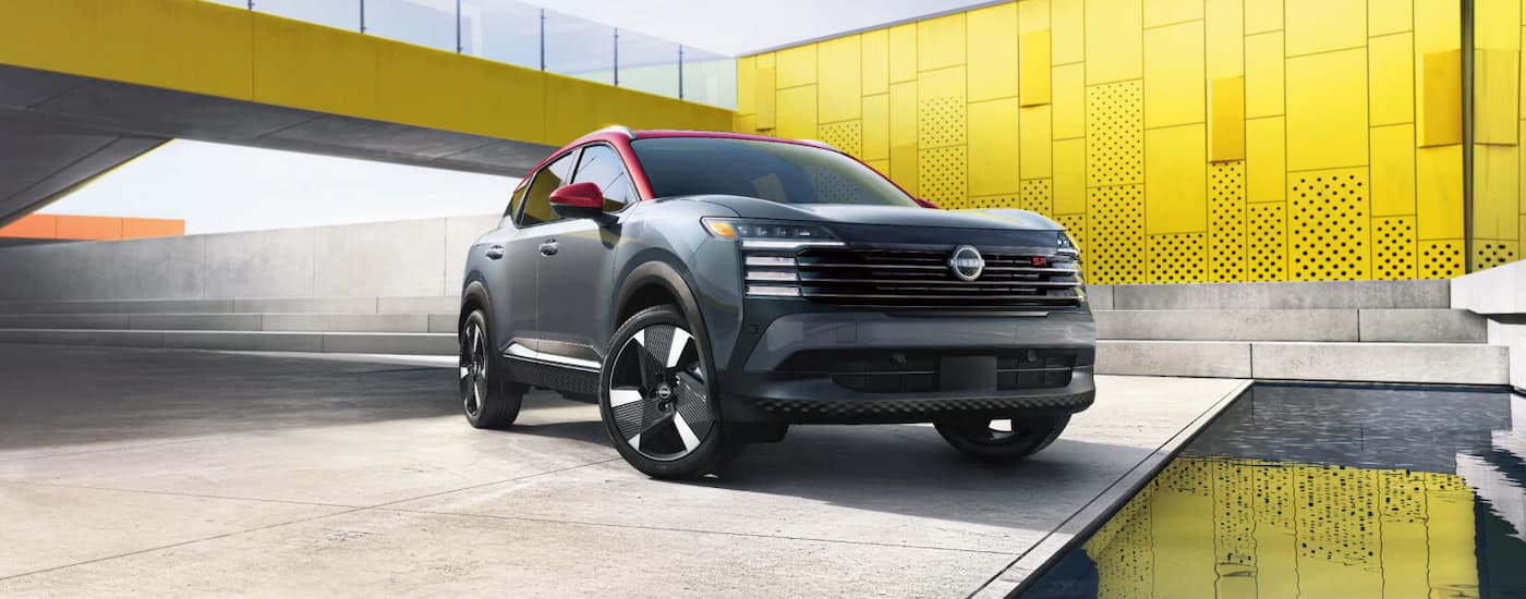 A red and gray 2025 Nissan Kicks parked outside a building